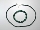necklace and bracelet made of green glass beads on a white surface