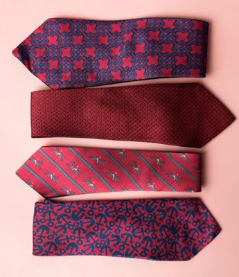 four ties are lined up in a row on a pink surface
