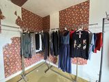 a photo of a clothes rack in a room with a wallpapered wall