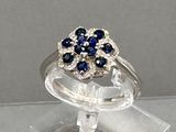 une bague ornée de pierres bleues et blanches, montée sur un support transparent
