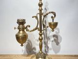 an antique brass candelabra with three candles on a wooden table