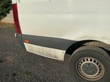 une camionnette blanche garée sur un parking avec des arbres en arrière-plan