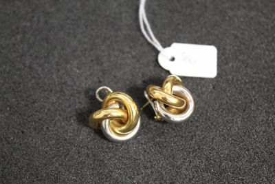 une paire de boucles d'oreilles en or et en argent posées sur une surface noire