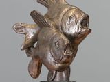 a statue of two fish on a marble base