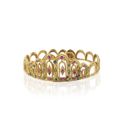une bague en forme de couronne dorée, ornée de pierres multicolores sur fond blanc