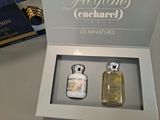 two bottles of perfume sitting in a box on a table