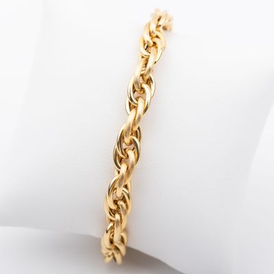 un gros plan d'un bracelet à chaîne dorée posé sur une serviette blanche