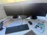 a desk with two monitors and a keyboard on it