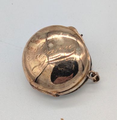 une petite montre de poche en argent posée sur une surface blanche