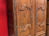 a wooden armoire in a room with a red wall