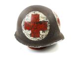 an old helmet with a red cross painted on it on a white surface