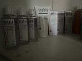 Des flacons de soins pour la peau sont alignés sur une étagère dans une salle de bains