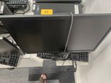 une personne debout devant un écran d'ordinateur et un clavier