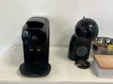 une cafetière noire posée sur un plan de travail, à côté d'un bol argenté
