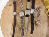 many different watches on a wooden board with a yellow ribbon