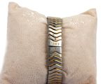 a gold and silver bracelet on a white pillow