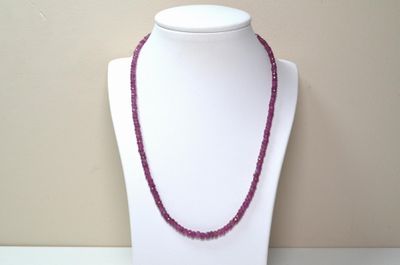 collier de perles violettes sur un mannequin à socle blanc