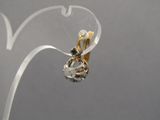 a pair of gold and diamond earrings hanging from a clear piece of glass