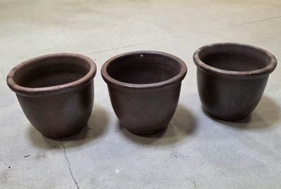 trois pots marron posés par terre dans une pièce