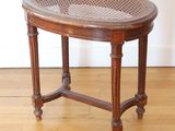 a small wooden table with a woven top on a hard wood floor