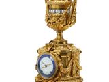 a gold clock on a pedestal with a crown on top