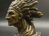 un gros plan sur une statue en bronze représentant un homme coiffé d'une coiffe