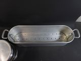 a metal pan with a strainer and a lid on a table
