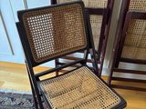 three folding chairs with woven seats in a room with a rug on the floor
