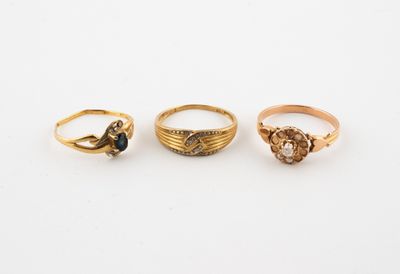 three gold rings, one with a black diamond and one with a white diamond, on a white background