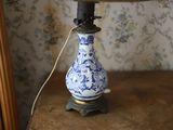 un vase bleu et blanc posé sur une table sur laquelle se trouve une lampe