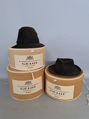 trois chapeaux noirs sont posés sur une boîte en carton