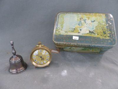 une petite boîte en fer-blanc avec une horloge à côté d'une cloche