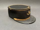un chapeau noir orné d'une bordure dorée, posé sur une surface grise