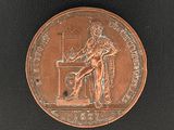 une image représentant une médaille de bronze sur laquelle figure un homme assis à un bureau