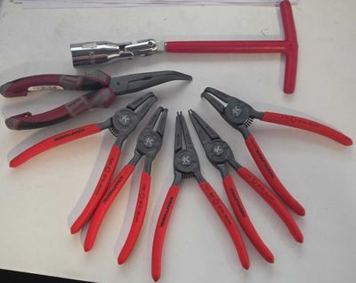 plusieurs pinces et tenailles posées sur une table, à côté d'un marteau