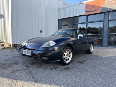 une photo d'une voiture de sport bleue garée devant un immeuble