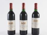three bottles of wine are lined up on a white surface