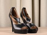 black high heeled shoes on a wooden table with a curtain in the background