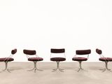 four red chairs sitting in a row on top of a cement floor
