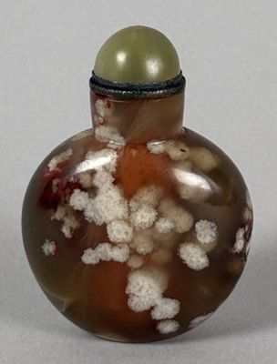 a small glass bottle with a green ball on top of it