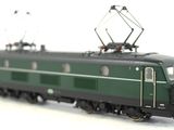 a green train that is on the tracks on a white surface