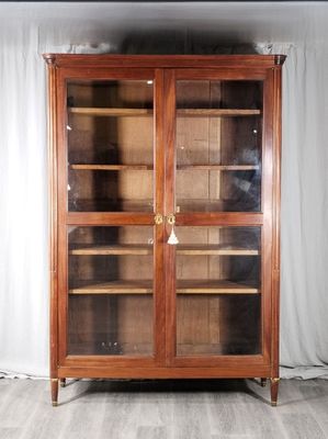 un grand meuble en bois avec des portes en verre dans une pièce