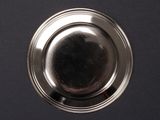a silver plate on a black surface with a black background