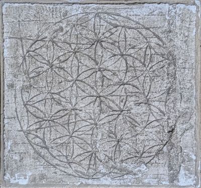 a close up of a stone with a flower of life carved into it