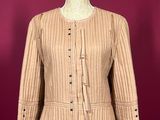 a beige jacket on a mannequin stand against a red wall