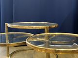 three glass and brass coffee tables on a wooden floor