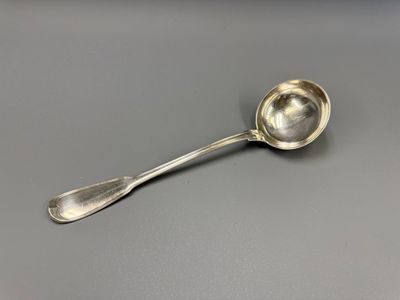 une cuillère en argent avec un manche de cuillère sur une surface grise