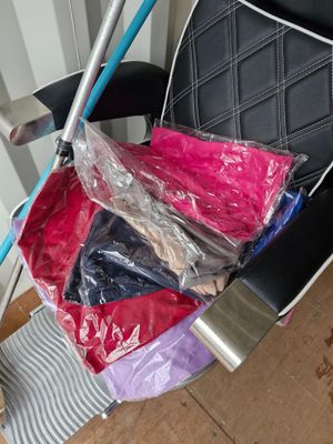 a black chair with a blue handle and a bag of clothes in it