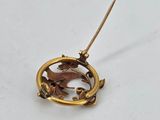 a close up of a gold brooch with a bird on it