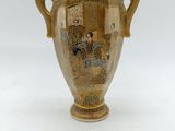 a gold vase with a painting on it on a white surface